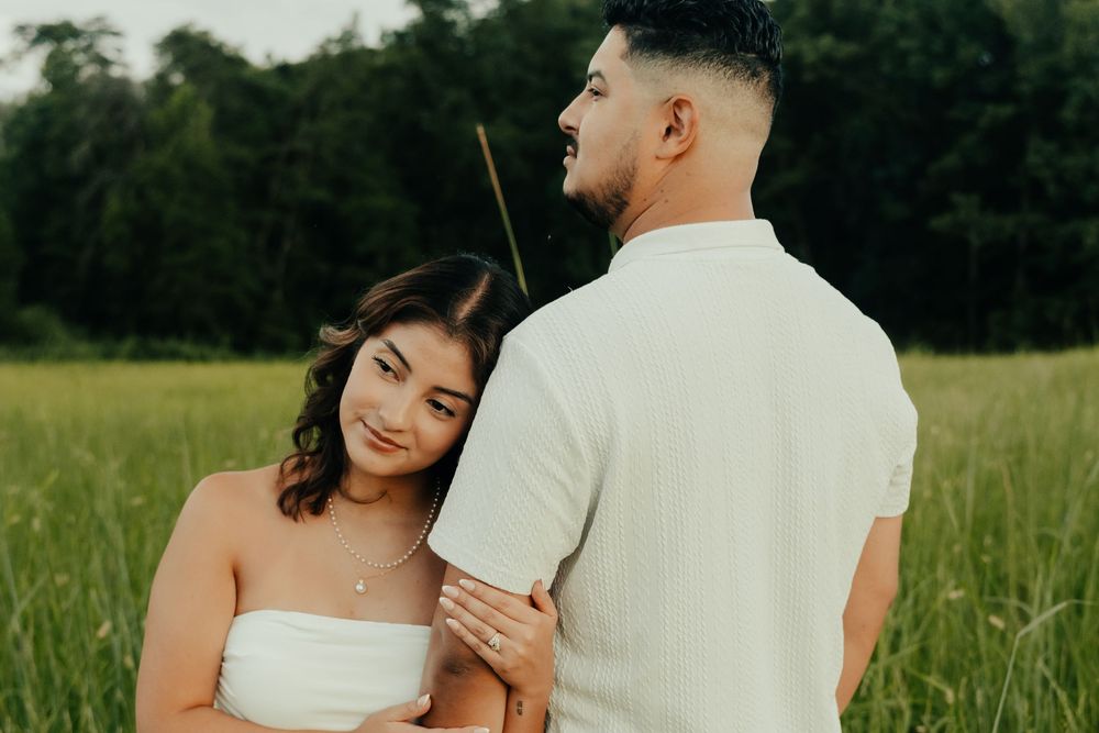 A couple in wedding attire shares tender moments in a lush green field during a romantic outdoor photo session.