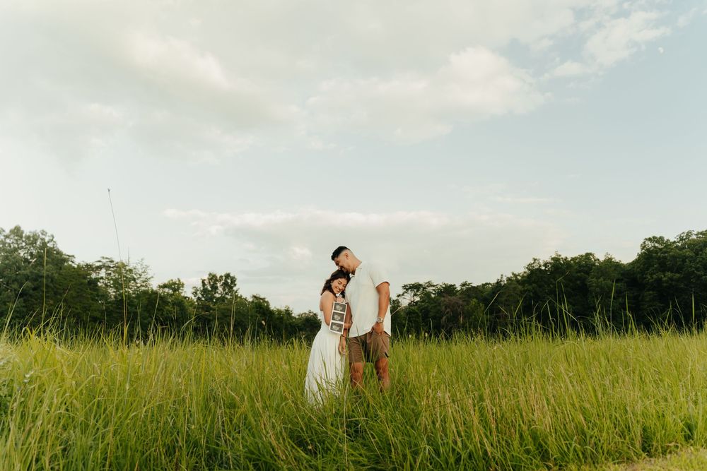 Couple walking through a serene golden meadow at sunset with tall grass swaying in the breeze.